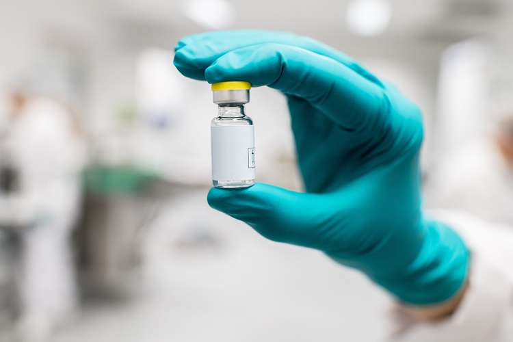 Gloved hand holding a vial of Johnson and Johnson COVID-19 vaccine candidate