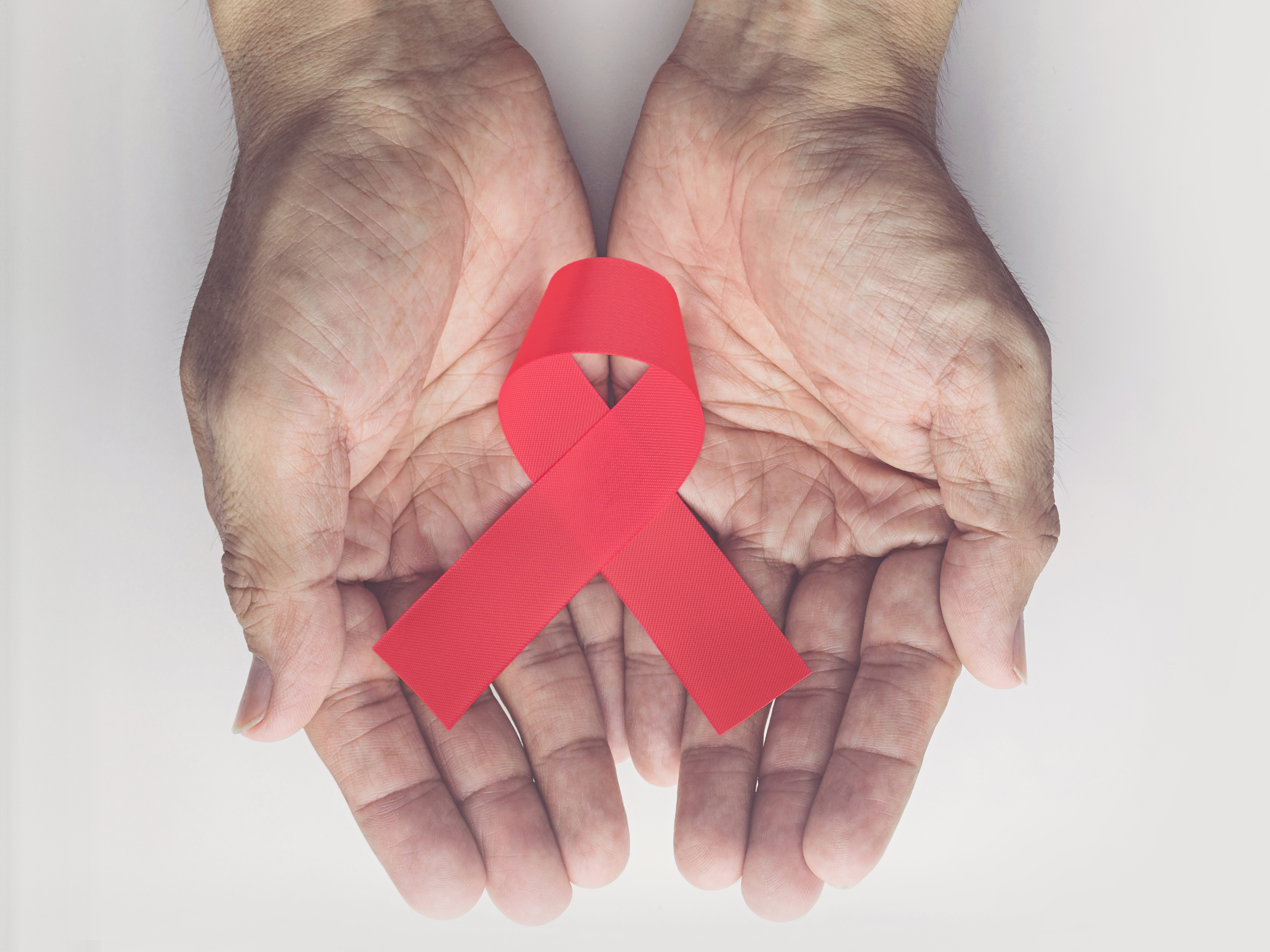 hands cupping a red AIDS ribbon