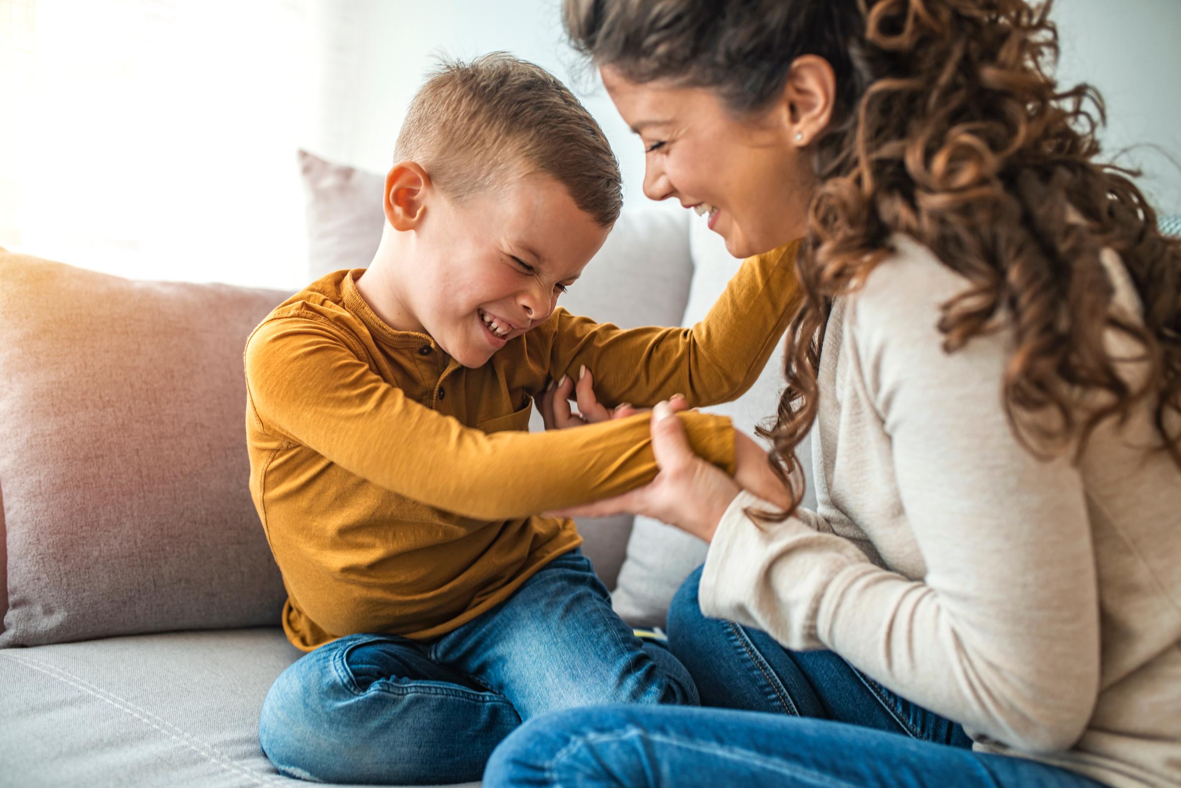 Mother and son playing and laughing together in sunny living room