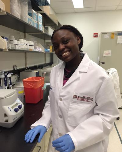 Kevina in the lab wearing a lab coat.