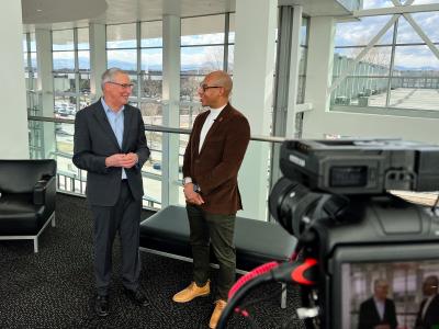 Two people talking with a video camera in the foreground.