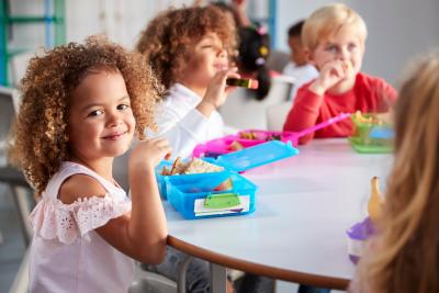 Children sit around a table eating lunch