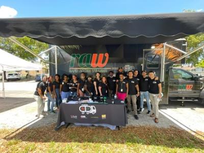 Group of people standing together looking at the camera, under a large tent.