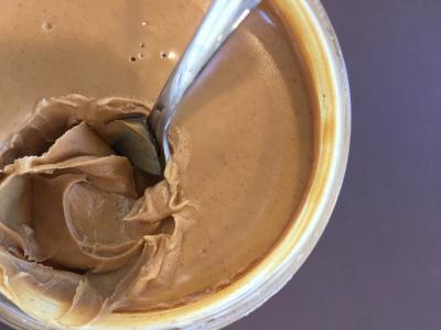 Container of peanut butter with a spoon.