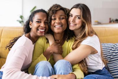 Photo of three young women smiling and embracing