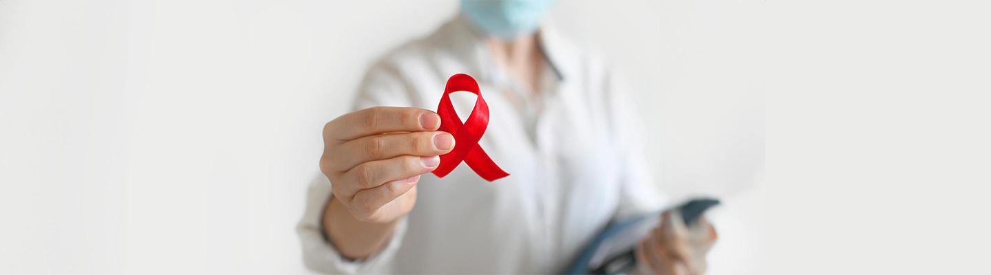 hand holding a red HIV ribbon