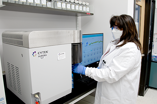 Rebecca processes a stained and fixed whole-blood sample on the Cytek Aurora Flow Cytometer in the BSL-2 laboratory.