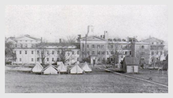 The (west facing) rear of the Marine Hospital, Stapleton, Staten Island, New York, where the Hygienic Laboratory was located from 1887–1891. Isolation tents for tuberculosis patients are visible behind the building