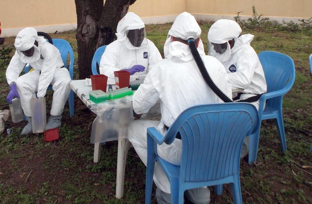 Four scientists sitting at table doing lab work in Mali field