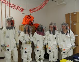 The image shows students trying on positive-pressure research suits in the BSL-4 training room at NIAID’s Rocky Mountain Laboratories.