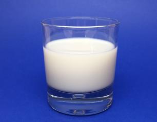 Clear glass of milk on blue background.