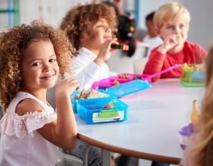 Children sit around a table eating lunch