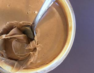 Container of peanut butter with a spoon.