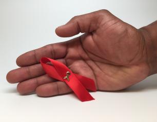 Red HIV awareness ribbon in a person's hand